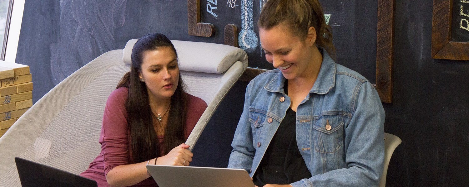 two female marketers discussing a project at a back table
